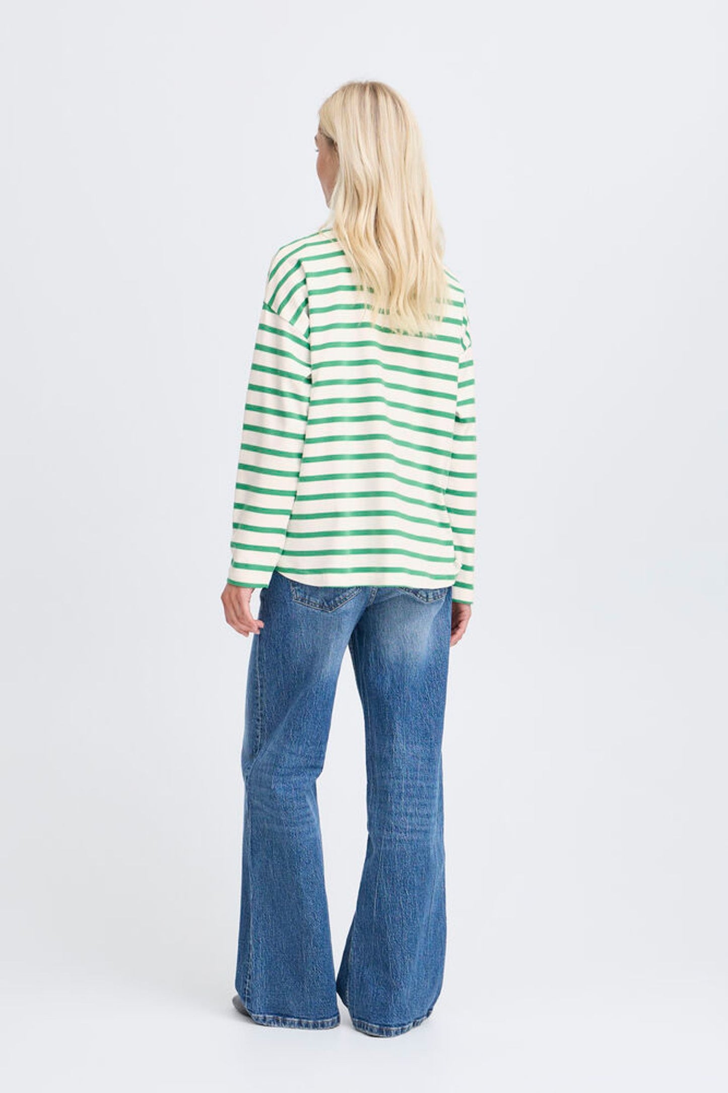 Person wearing a green and white striped shirt and blue jeans on a white background
