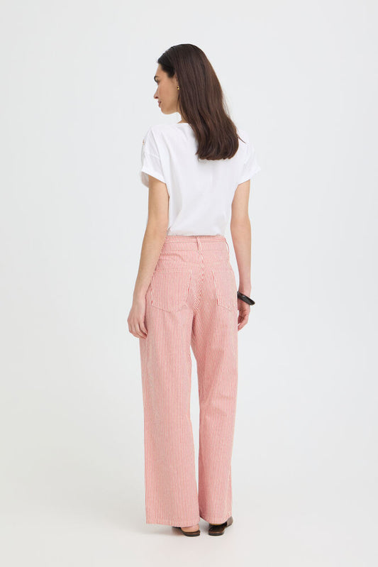 Woman wearing a white top and red striped pants on a white background