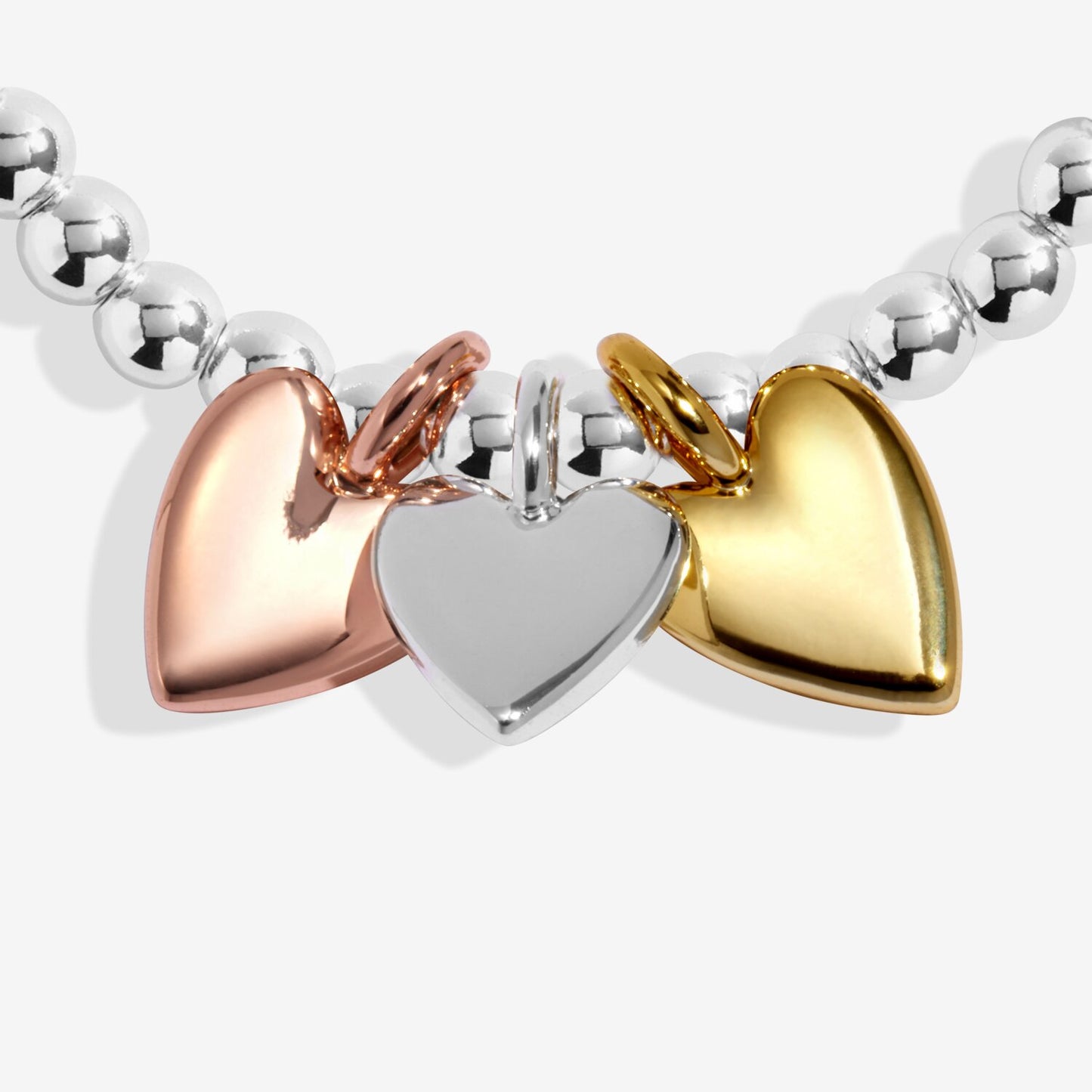 Bracelet with heart-shaped charms in rose gold, silver, and gold on a white background
