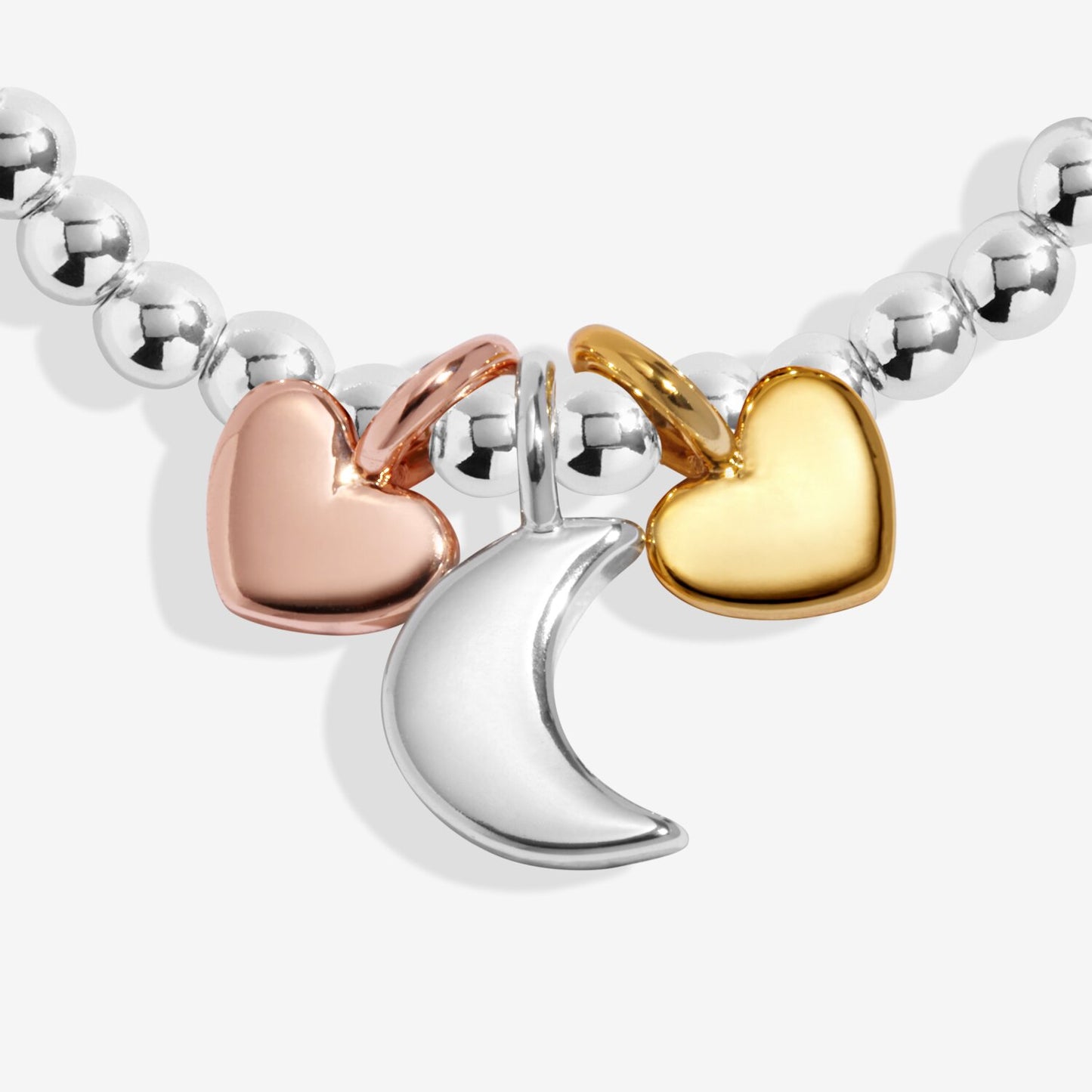 Bracelet with heart and moon charms in silver, rose gold, and gold on a white background