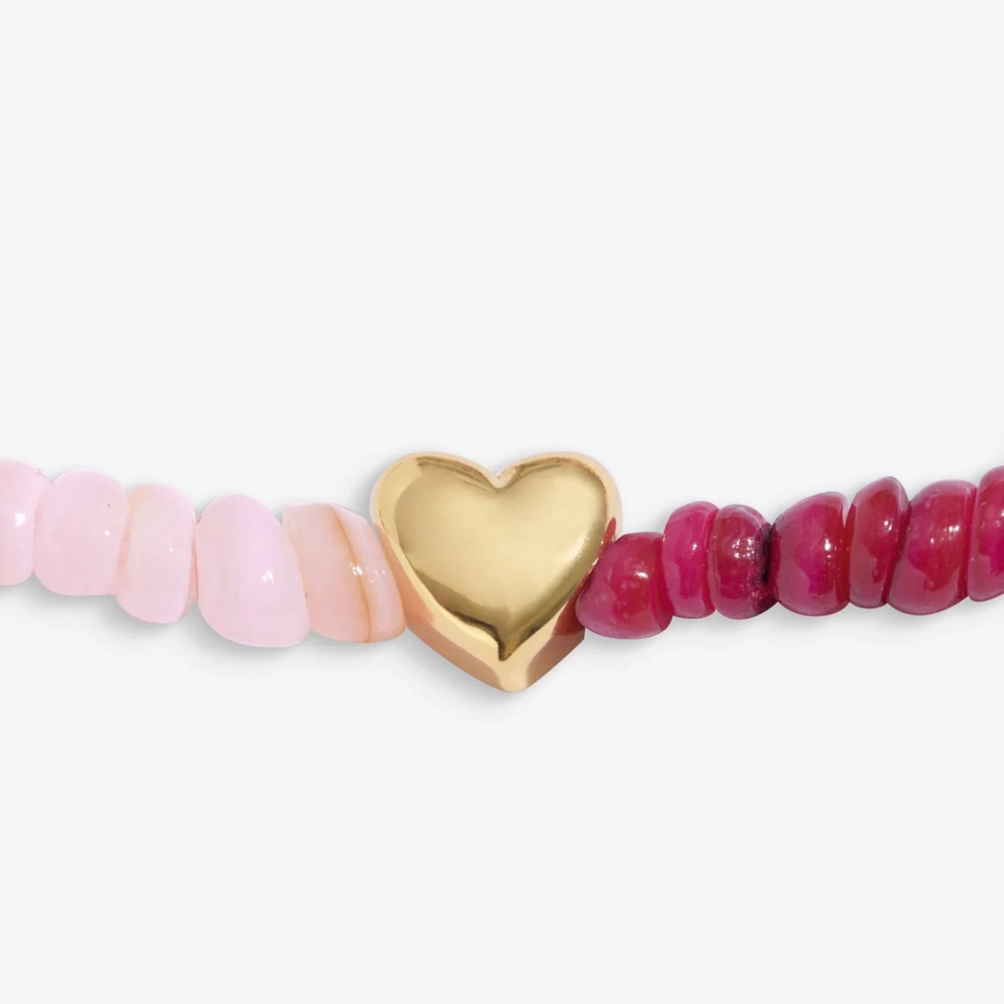 Pink beads and gold heart bead on white background