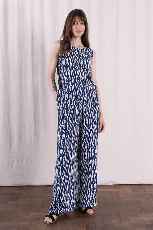 Woman wearing a blue and white patterned jumpsuit against a plain background