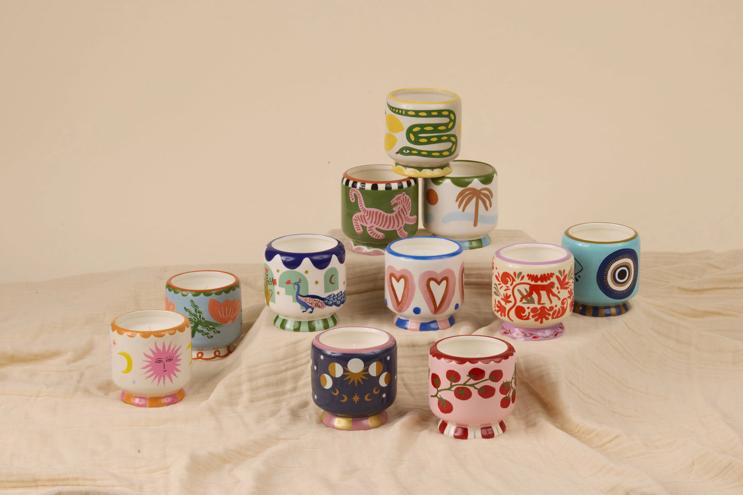 Collection of colorful ceramic cups with various patterns on a beige surface