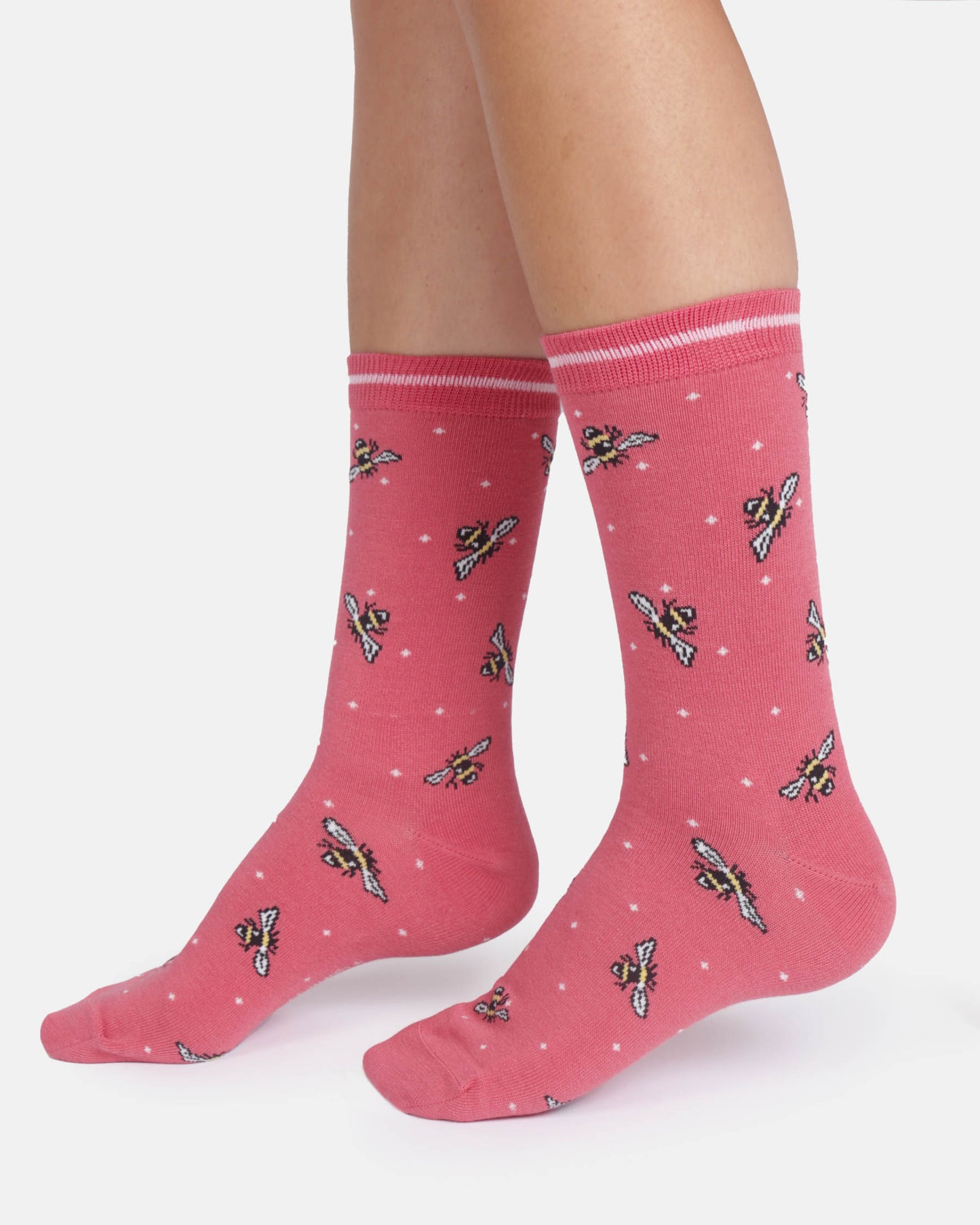 Pink socks with bee pattern worn by a person on a white background