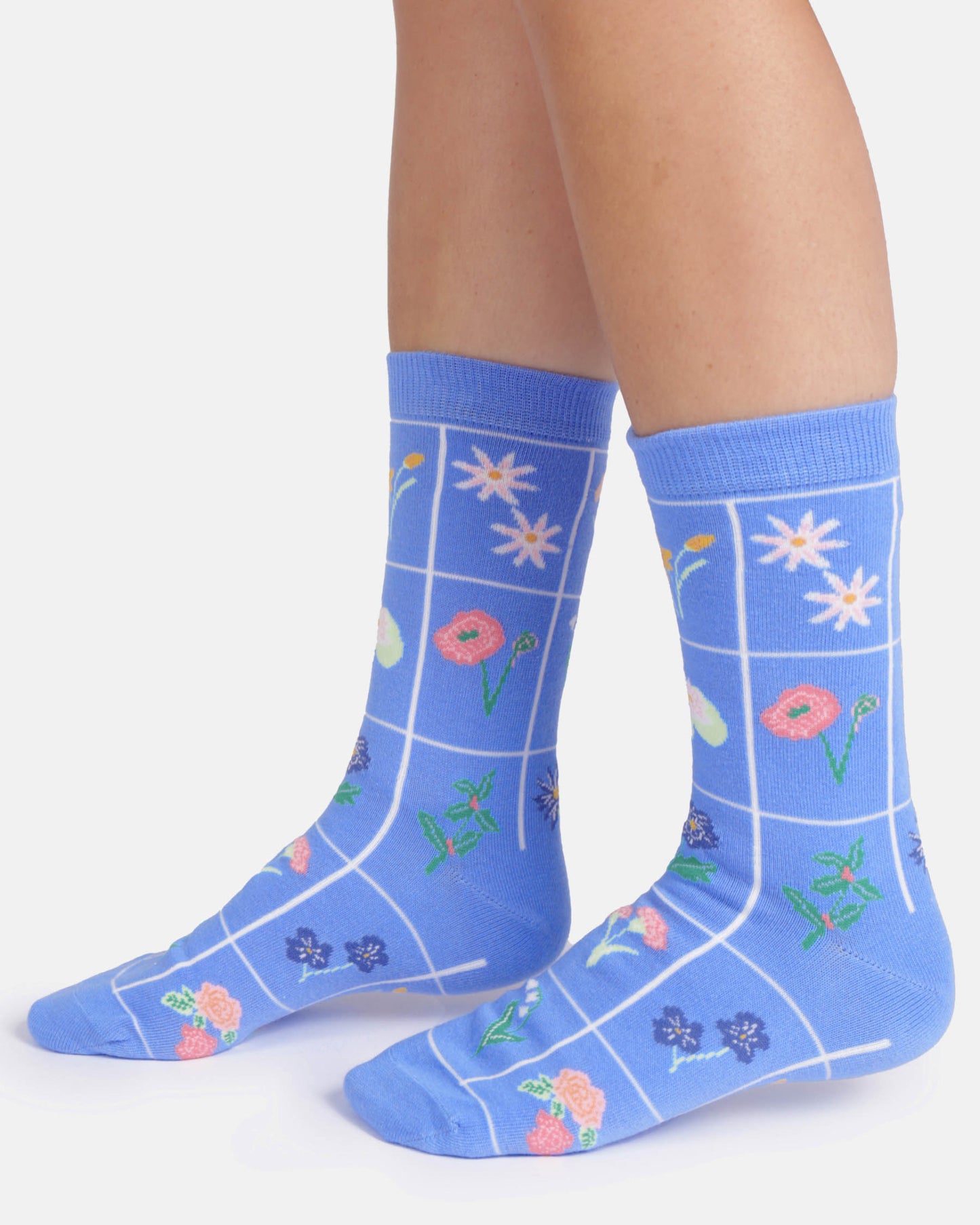 Blue socks with floral patterns worn by a person on a white background