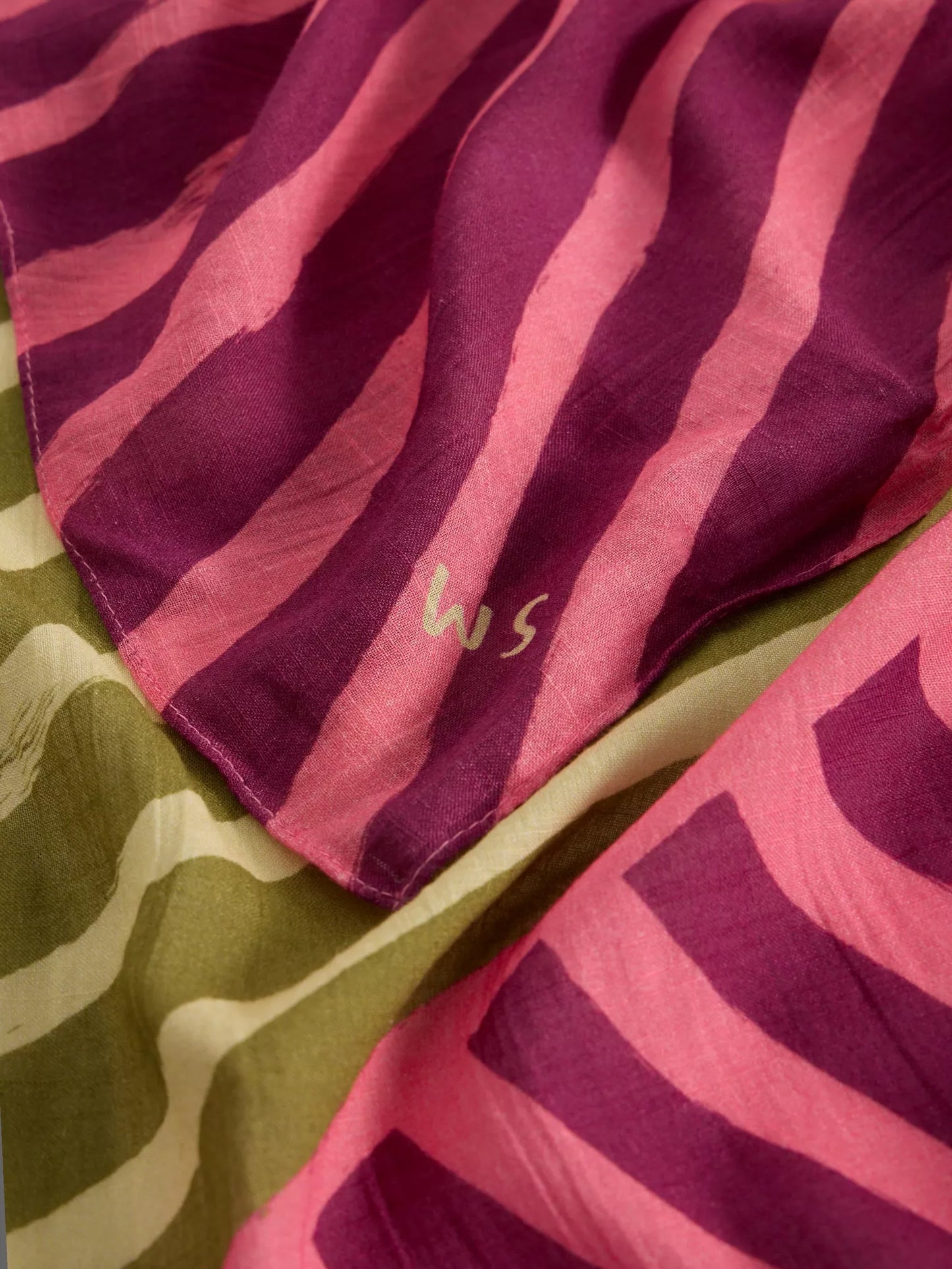 Close-up of a pink and green patterned fabric with a logo.