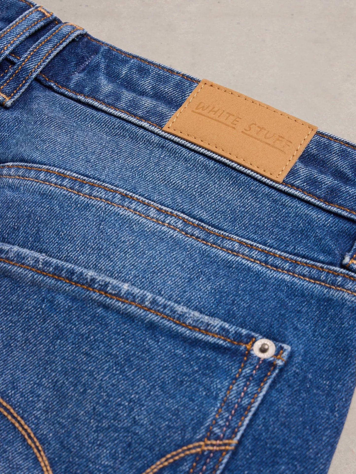 Close-up of blue jeans with a brown label on a gray background