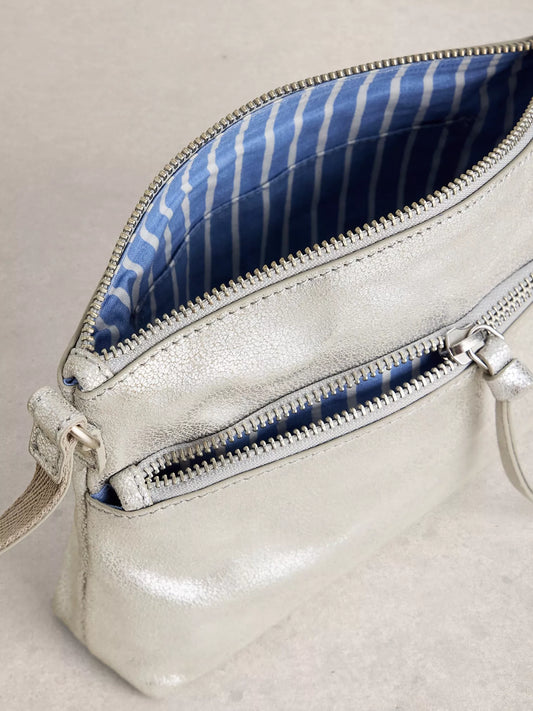 Silver handbag with blue striped interior on a light gray background