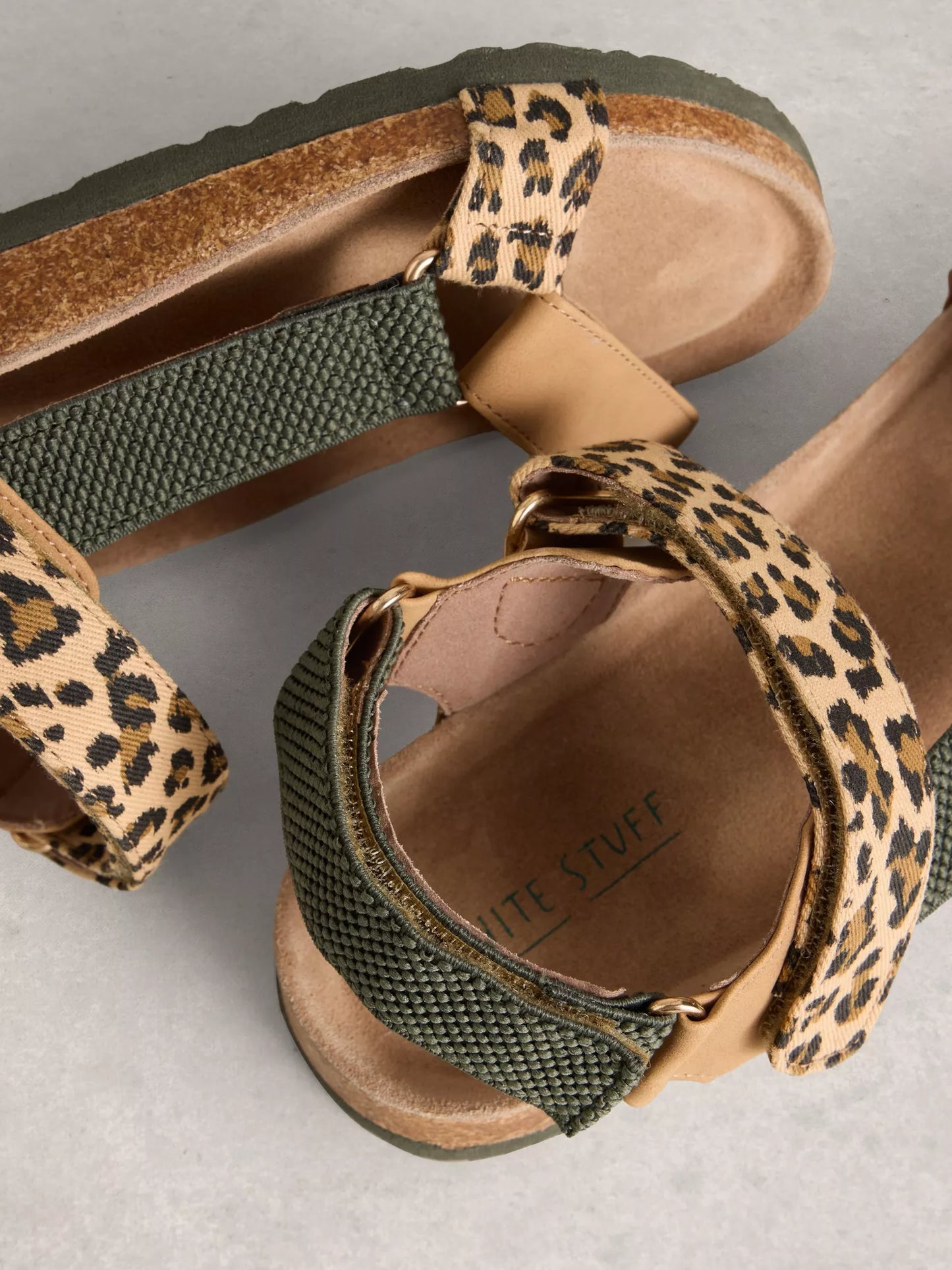Pair of sandals with leopard print straps on a neutral background