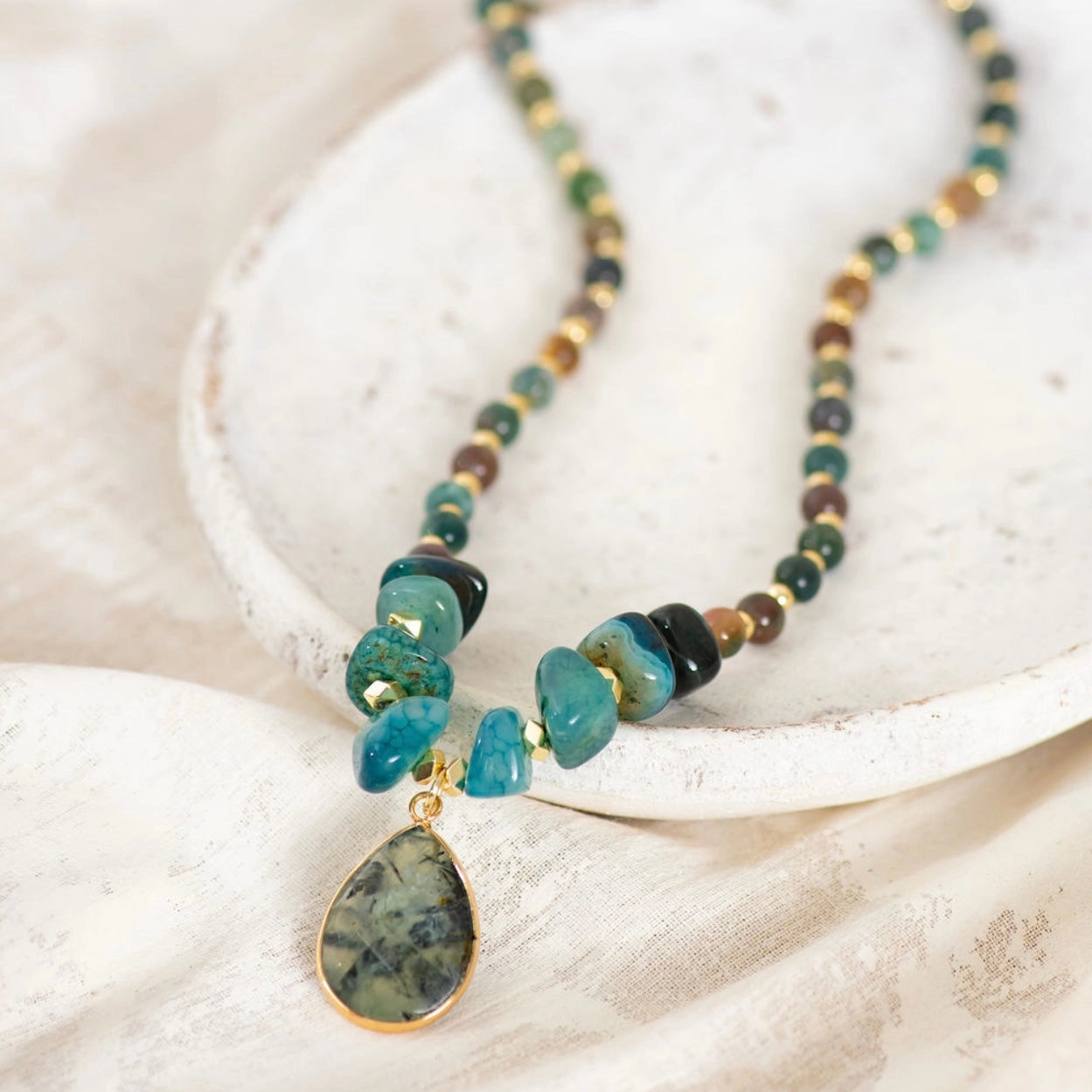 Necklace with beads and a pendant on a textured surface