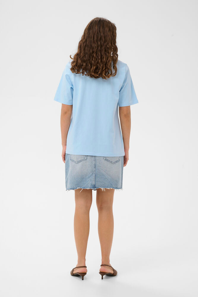 Person wearing a light blue t-shirt and denim skirt on a white background