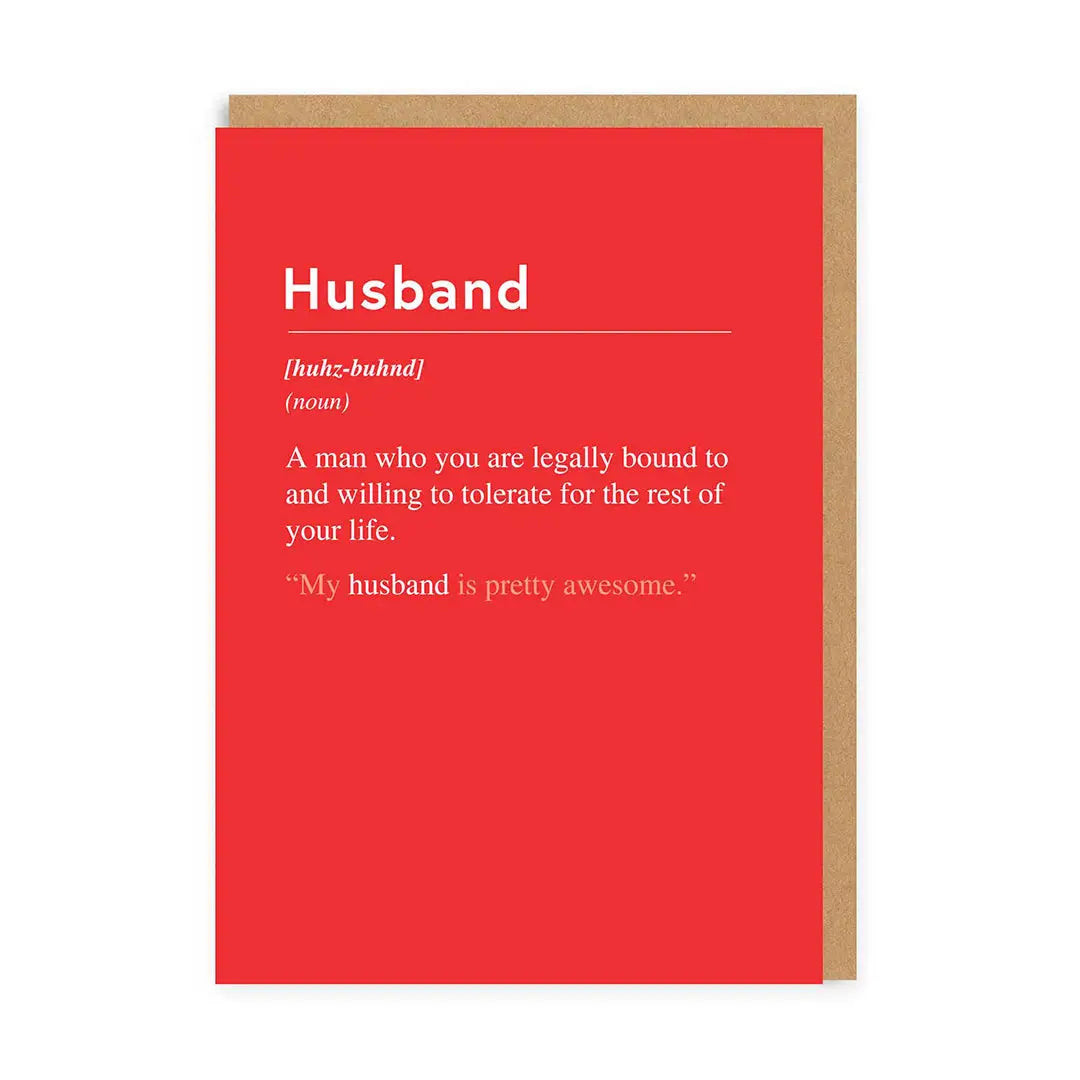 A red greeting card with the definition of 'husband' printed on it, including a quote about willingness to tolerate.