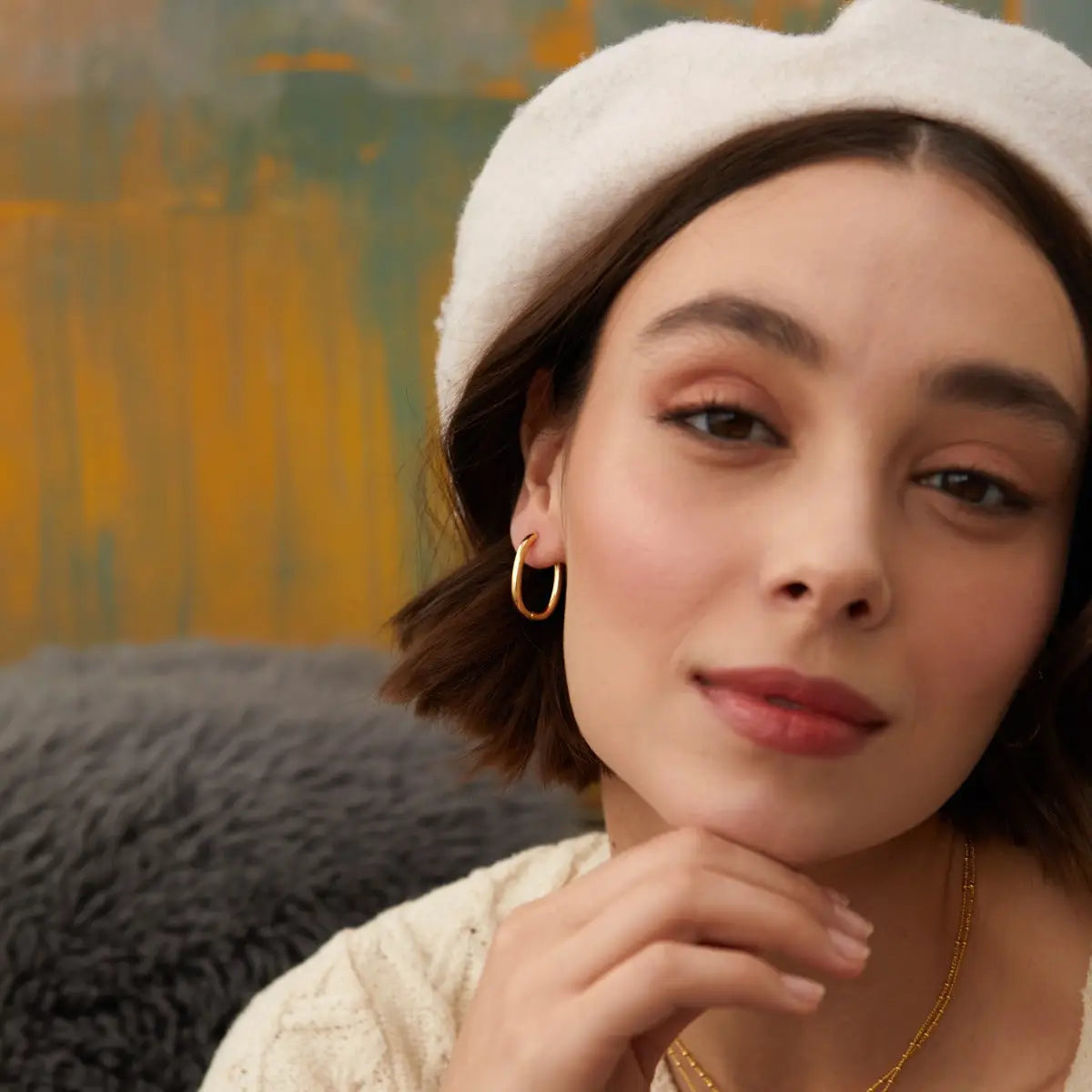 Woman wearing a white beret and gold earring with a blurred background