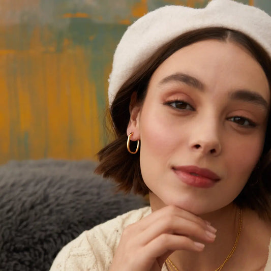 Woman wearing a white beret and gold earring with a blurred background