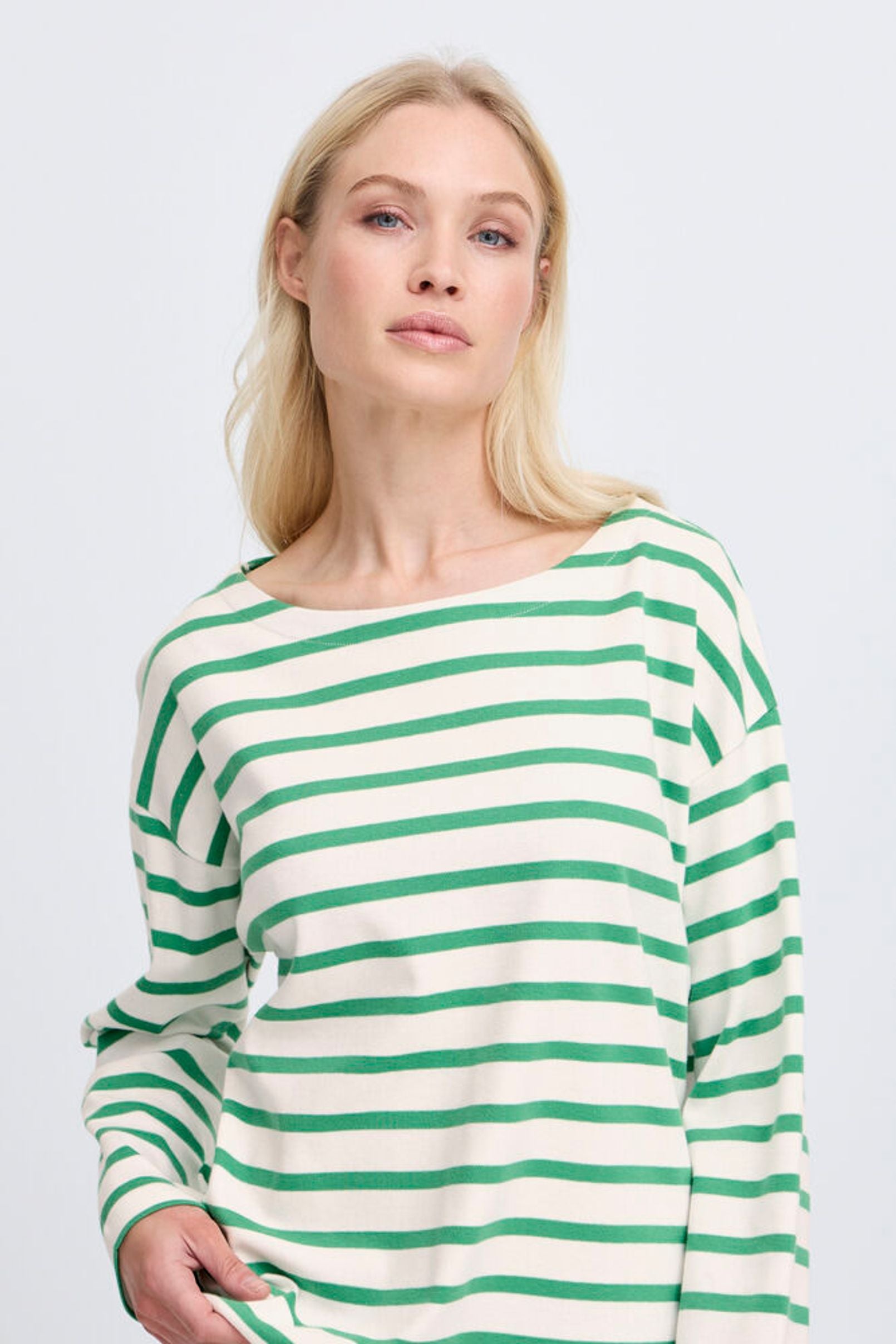 Woman wearing a green and white striped sweater on a light gray background