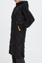 Black quilted coat worn by a person on a white background