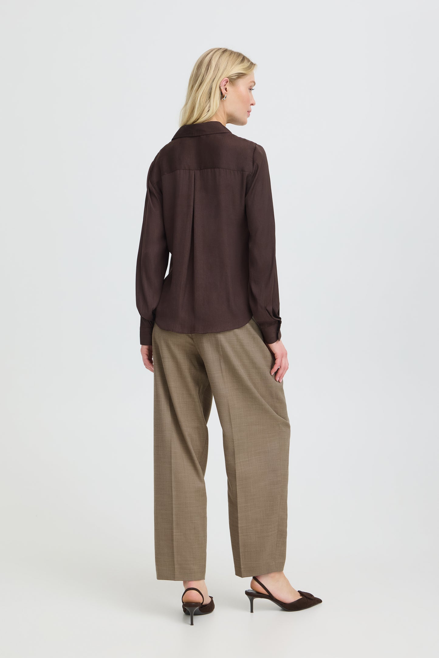 Woman wearing a brown shirt and beige pants on a white background