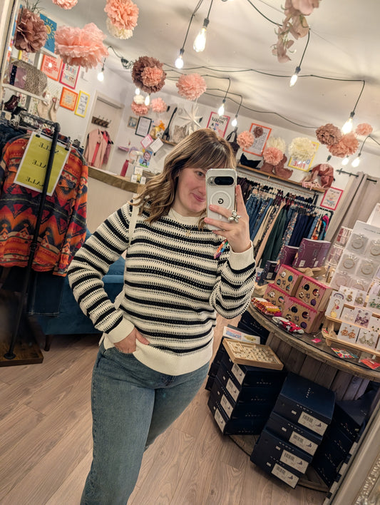 Person taking a mirror selfie in a clothing store with various items and decorations.