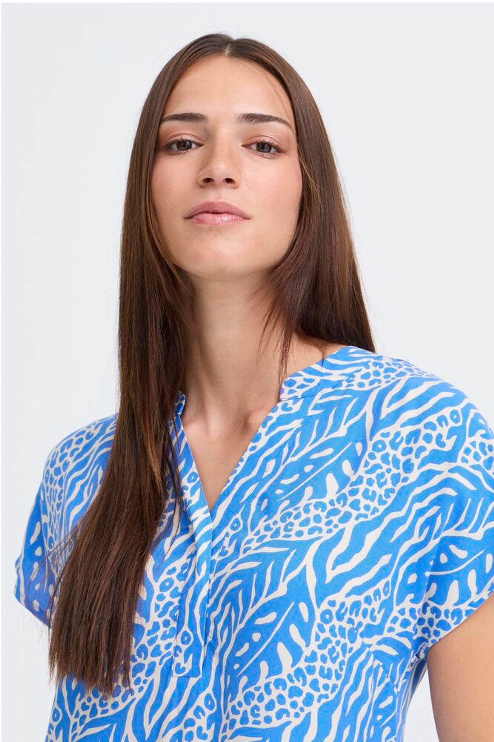 Woman wearing a blue patterned shirt against a white background