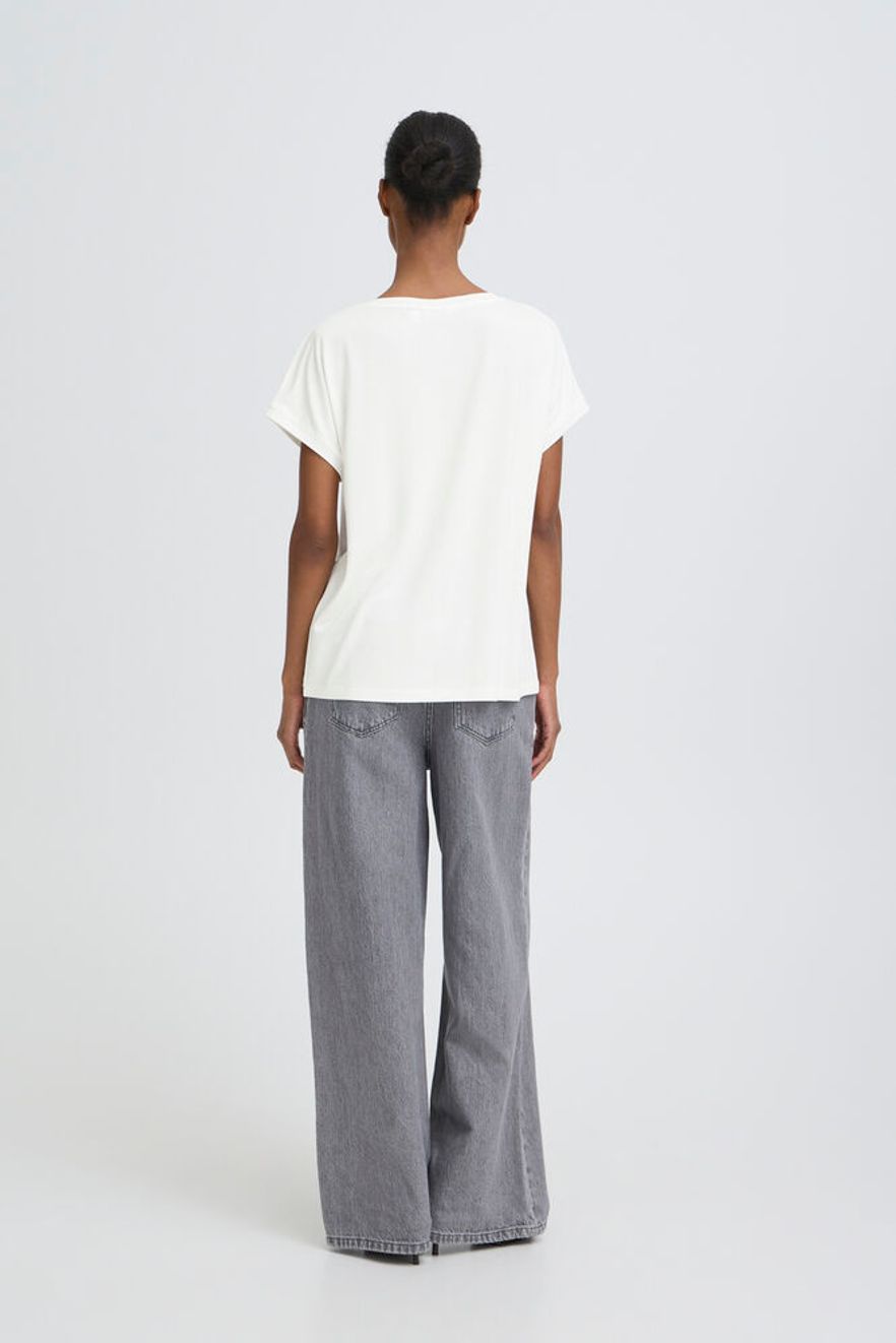 Person wearing a white top and gray pants on a white background