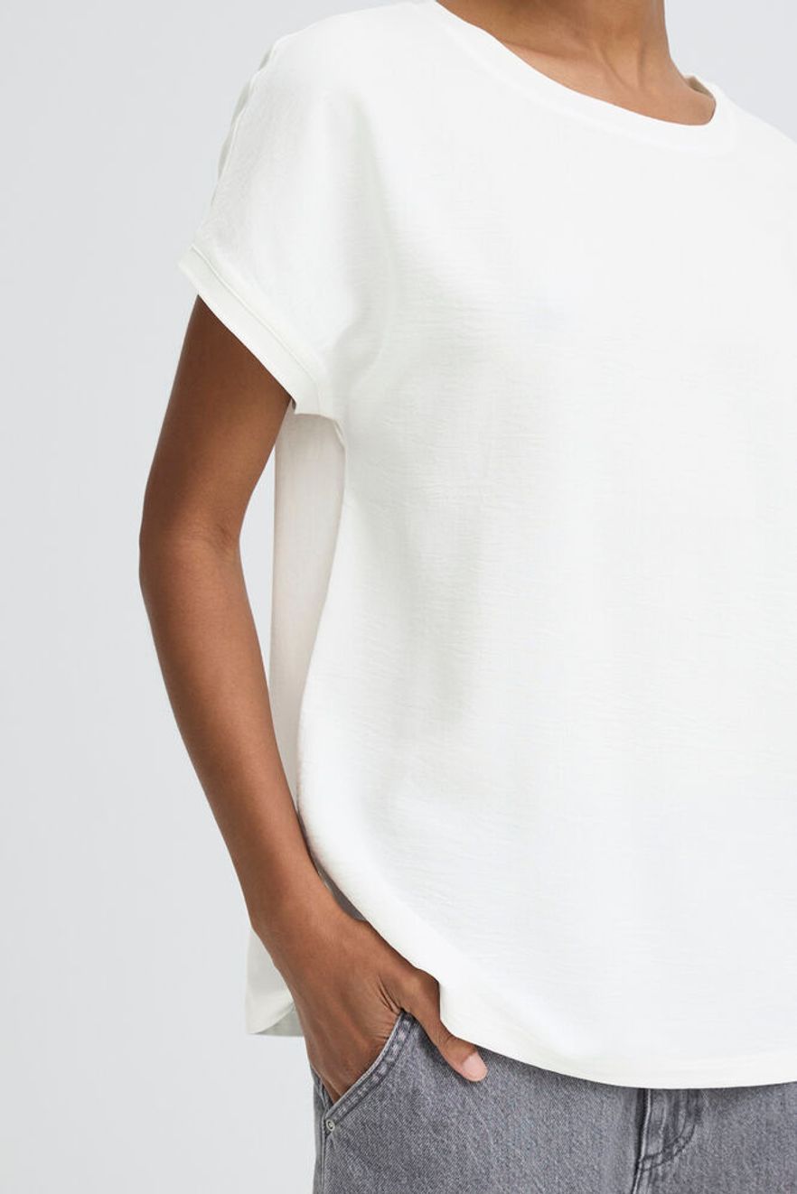 Person wearing a plain white t-shirt against a light gray background