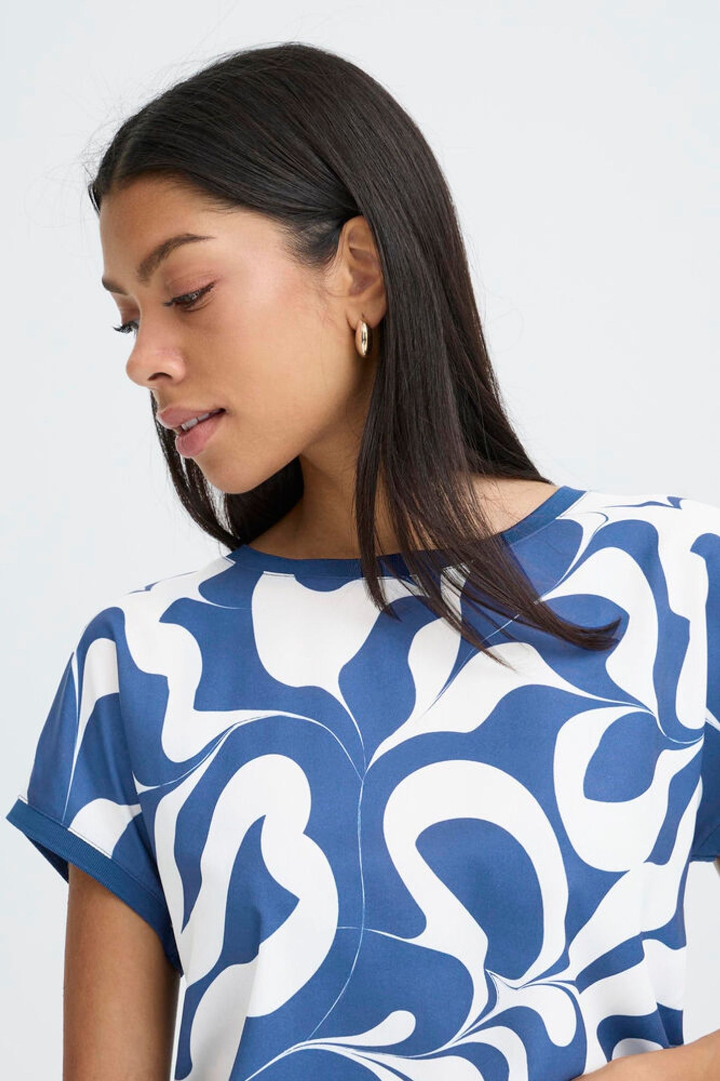 Woman wearing a blue and white patterned top against a plain background