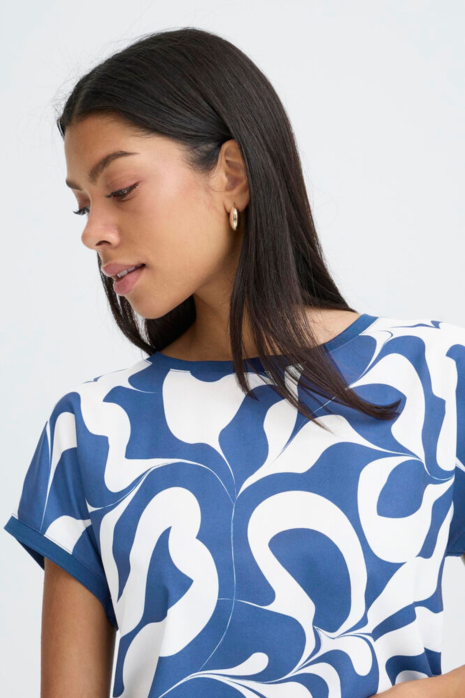 Woman wearing a blue and white patterned top against a plain background