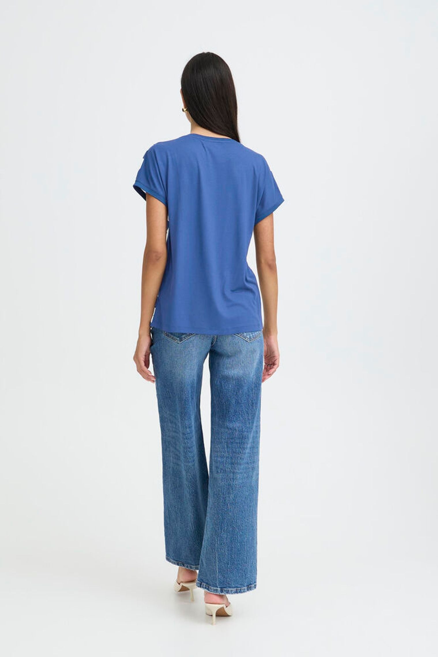 Woman wearing a blue t-shirt and jeans on a white background