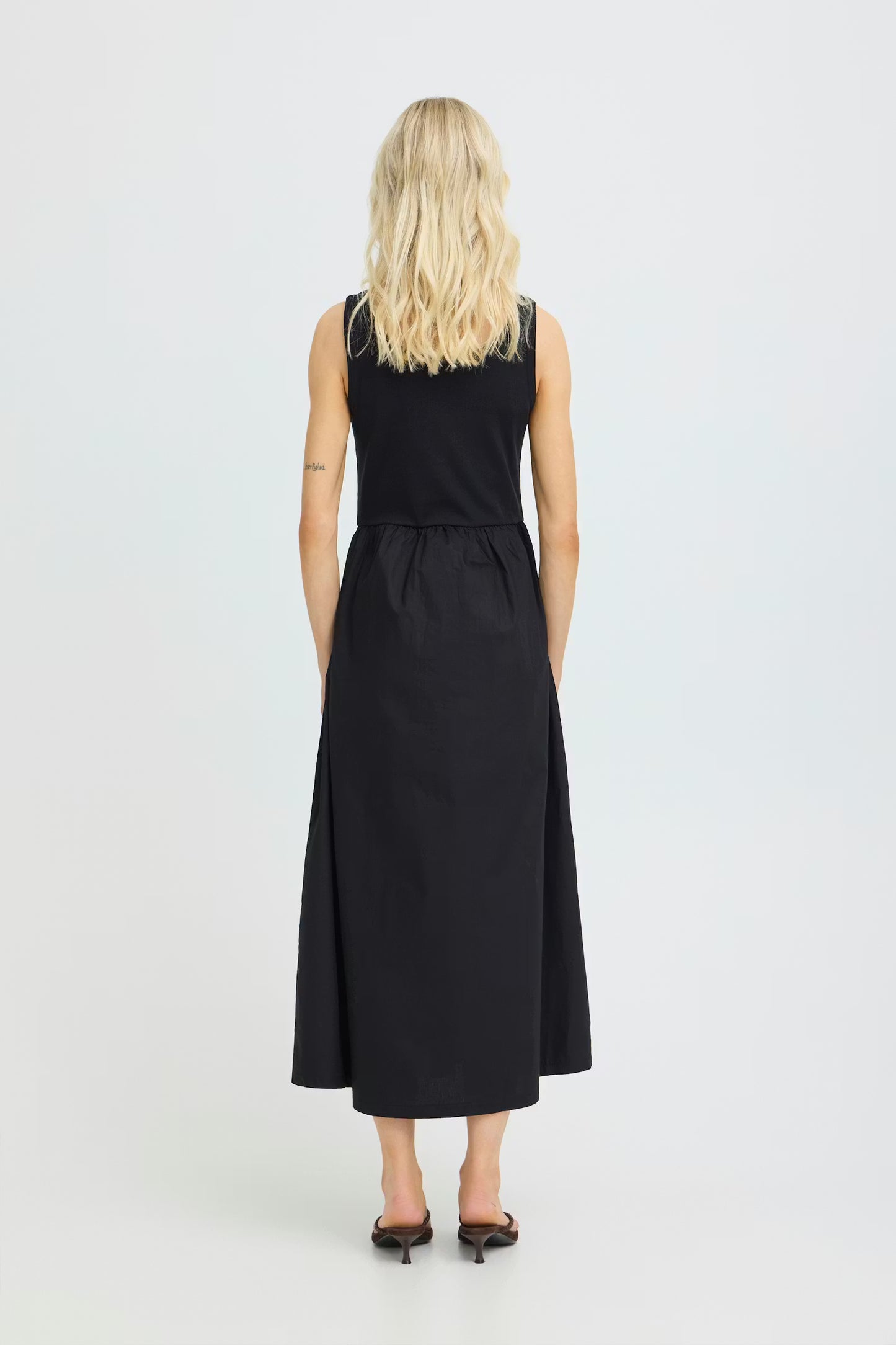 Person wearing a black sleeveless dress on a white background