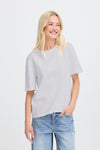Woman wearing a light gray t-shirt and blue jeans on a white background
