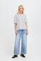 Woman wearing a light gray t-shirt and blue jeans on a white background