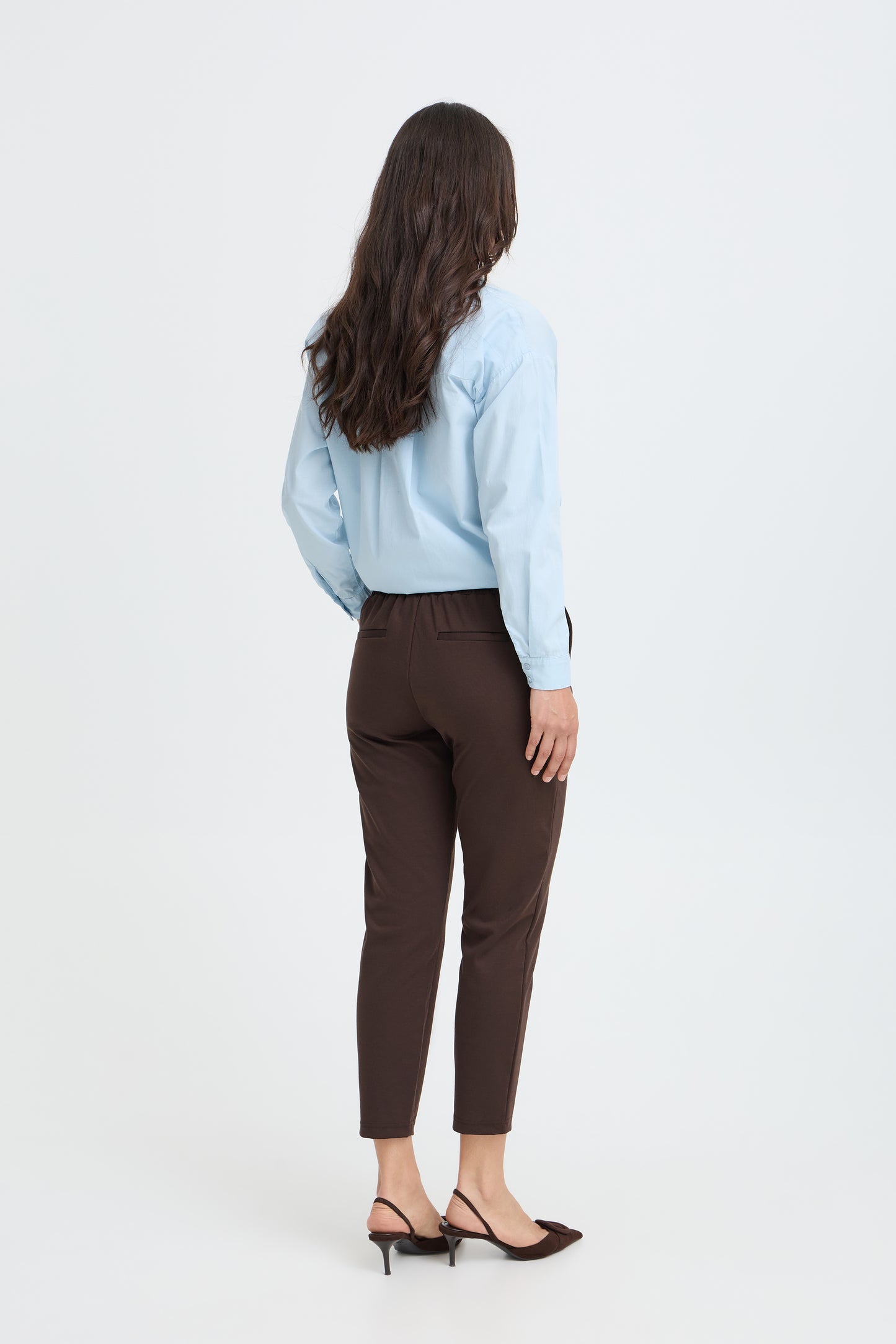 Back view of model wearing chocolate brown tapered trousers