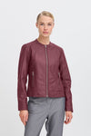 Woman wearing a burgundy leather jacket on a light grey background