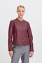 Woman wearing a burgundy leather jacket on a light grey background
