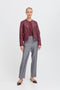 Woman wearing a burgundy jacket and gray pants on a white background