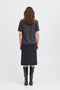 Person wearing a dark gray t-shirt and skirt with black knee-high boots on a white background