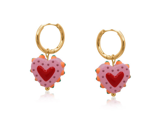Gold hoop earrings with pink heart-shaped charms on a white background