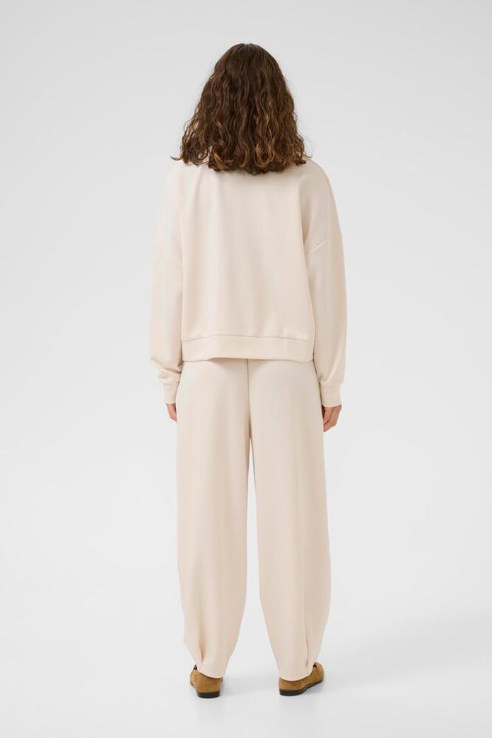 Person wearing a beige outfit on a white background