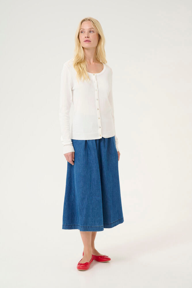 Woman wearing a white cardigan and blue skirt on a white background