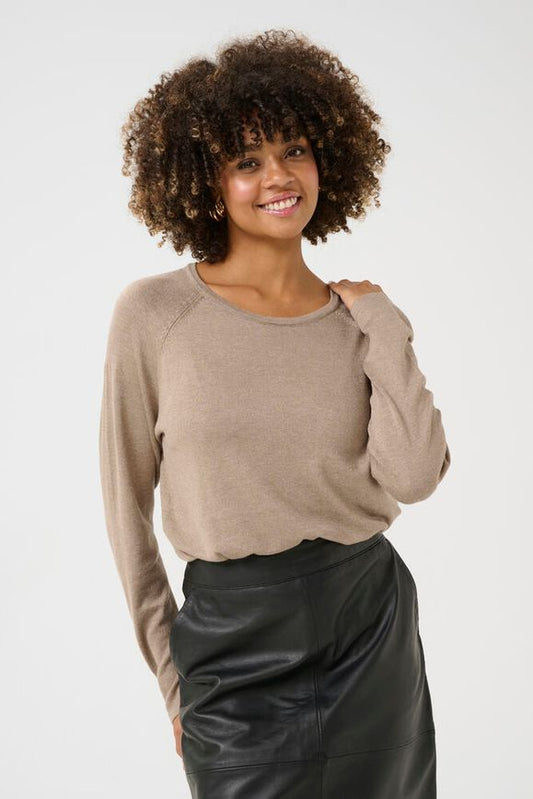 Woman wearing a beige sweater and black leather pants on a white background