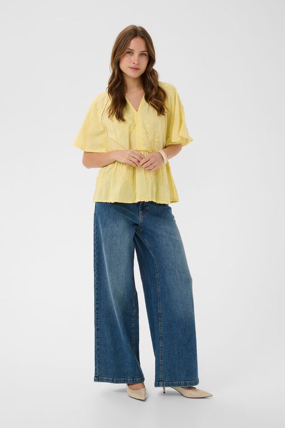 Woman wearing a yellow blouse and blue jeans on a white background