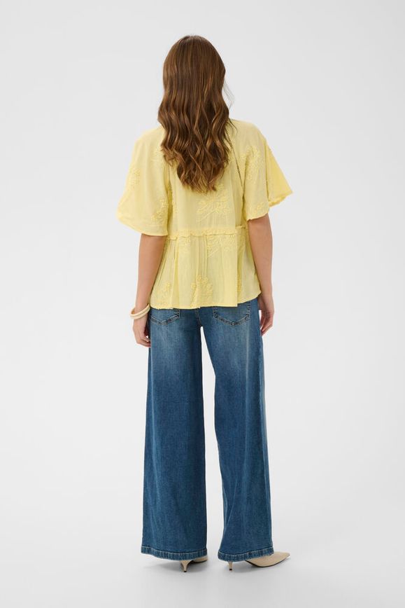 Person wearing a yellow blouse and blue jeans on a white background
