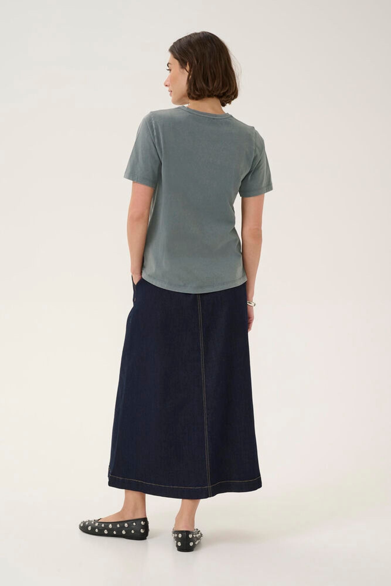 Person wearing a gray t-shirt and navy skirt on a white background
