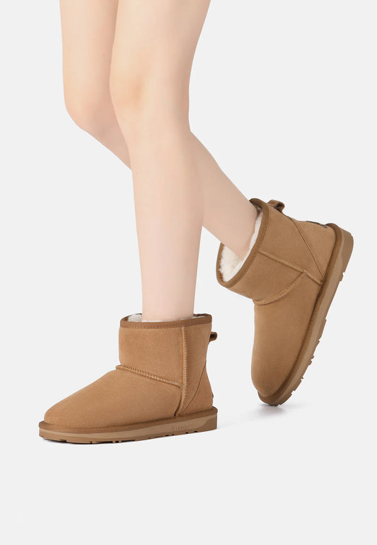 Tan sheepskin boots worn with a neutral background