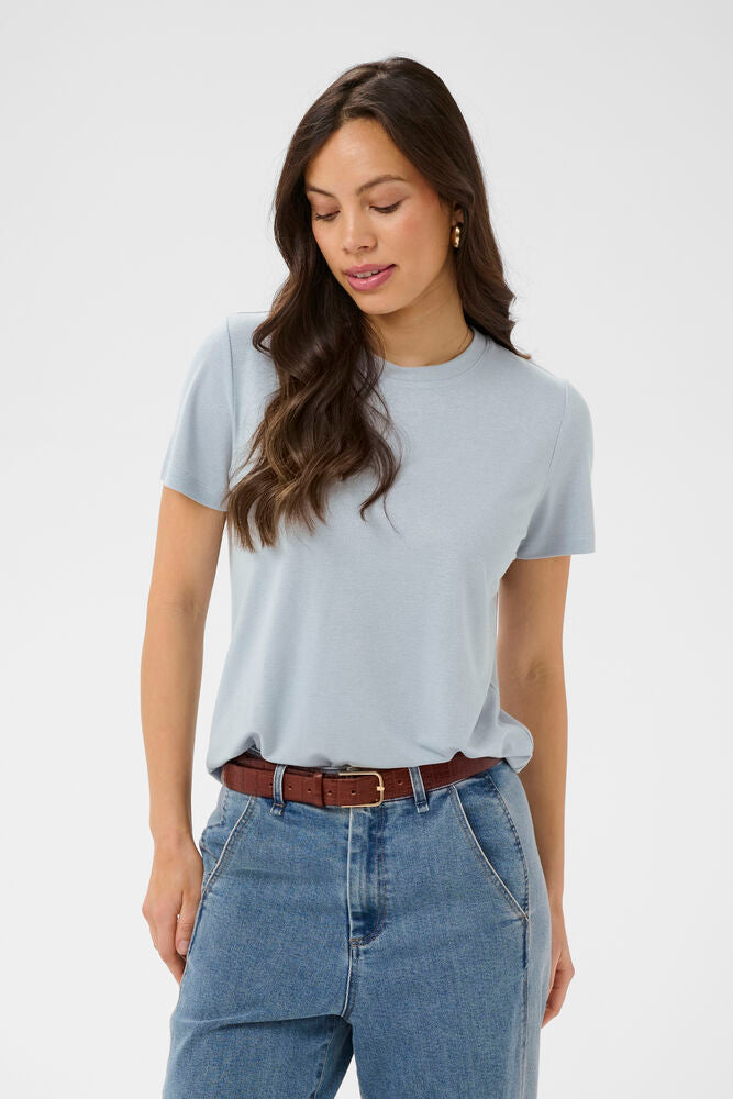 Woman wearing a light blue t-shirt and blue jeans on a white background