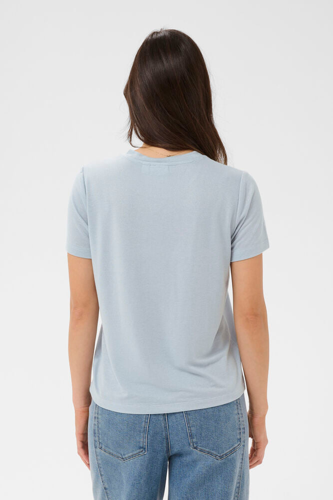 Woman wearing a light blue t-shirt and blue jeans on a white background