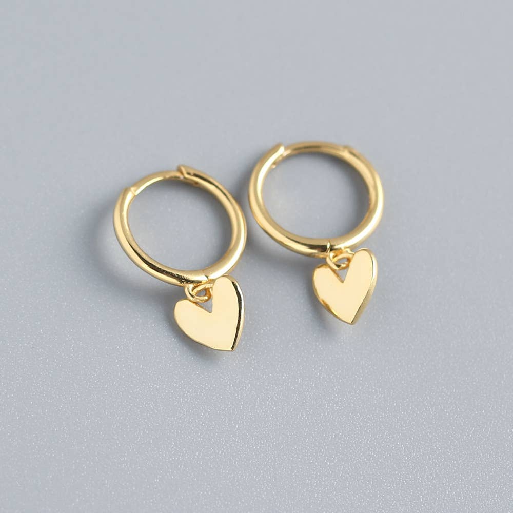 Gold hoop earrings with heart charms on a gray background