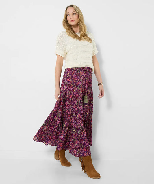 Woman wearing a white top and floral skirt on a plain background