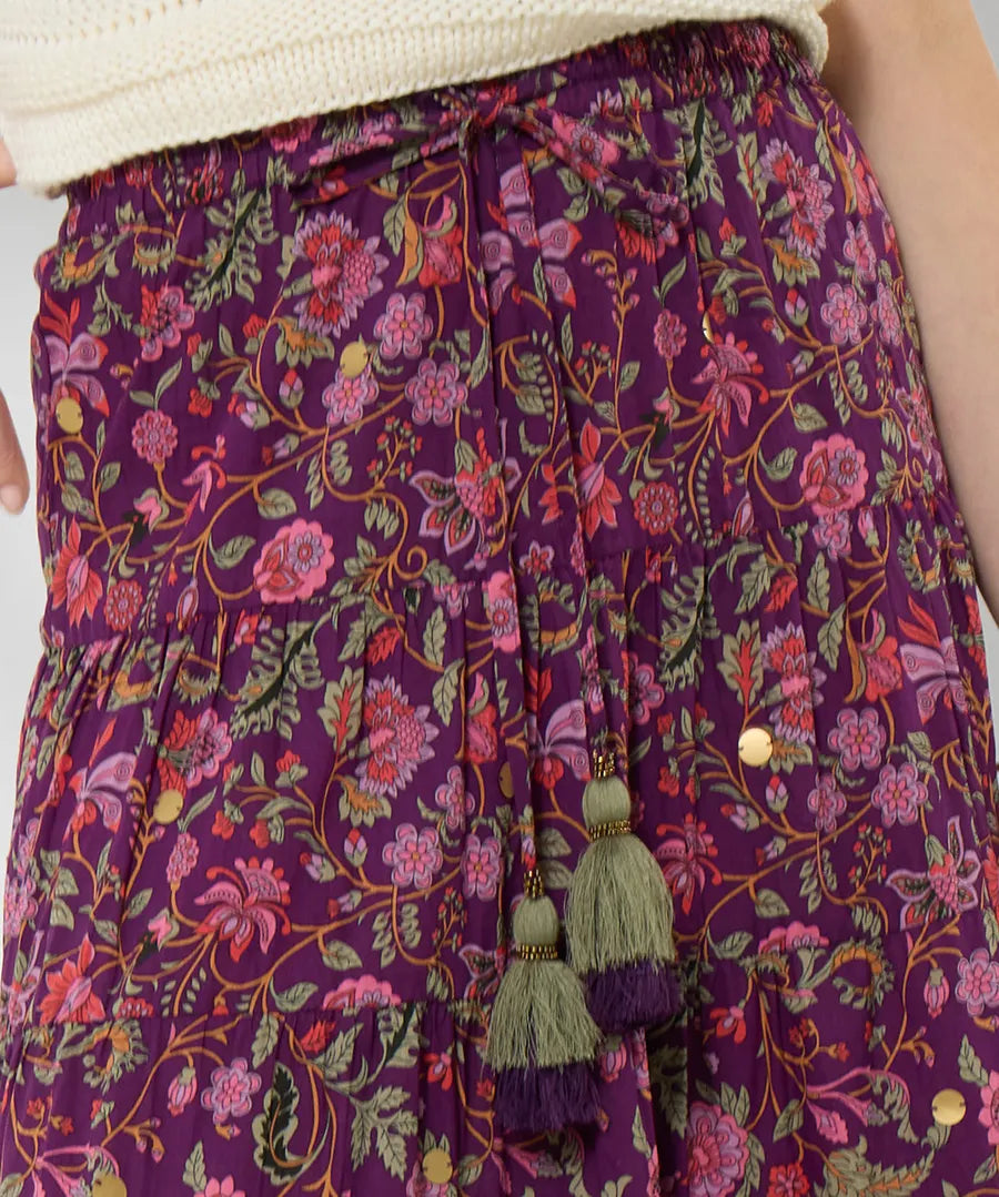 Purple floral pants with tassels and buttons on a plain background