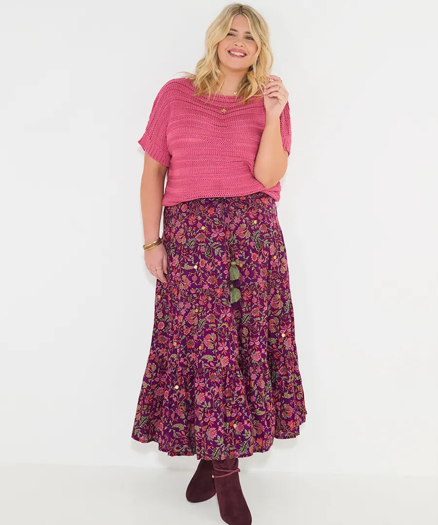 Woman wearing a pink top and floral skirt on a white background
